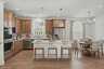 kitchen with wood cabinets, white countertops, stainless steel appliances, barstools, and dining table