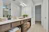 primary bathroom with double sink vanity, wood cabinets, tile flooring, and a glass shower
