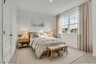 secondary bedroom with bed, nightstands, and curtains around large windows