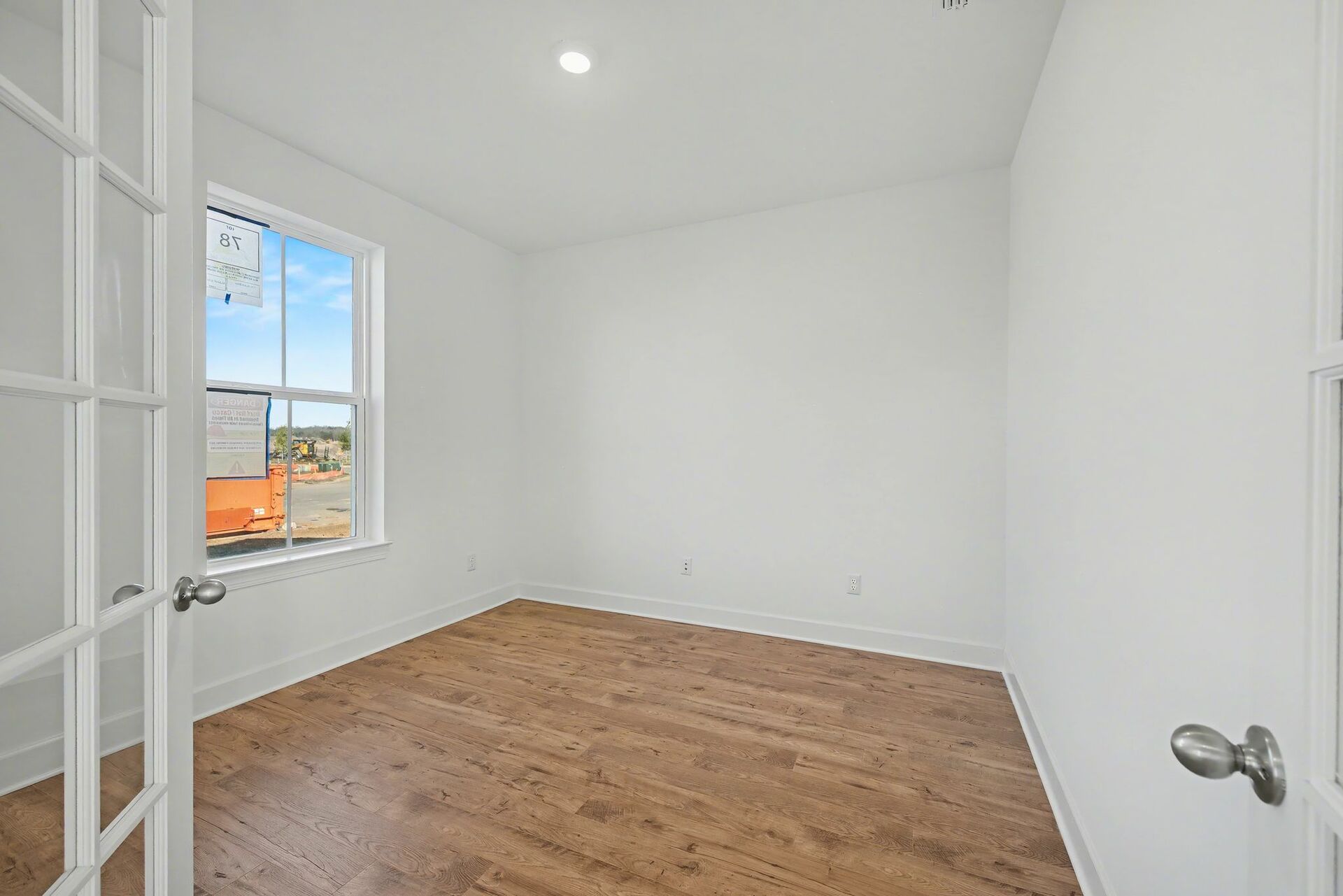 study with french doors, windows, and light wood flooring