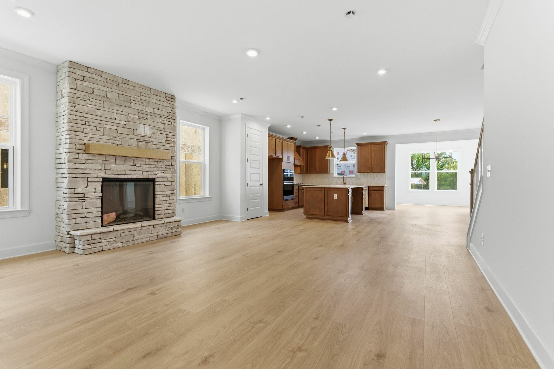 great room featuring stone fireplace with cedar mantle that opens into a spacious kitchen and morning room with large windows