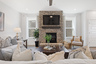 great room with wood floors, large windows, and stone fireplace