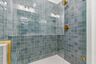 primary bathroom with light pewter blue mosaic shower tile and gold hardware, double sink vanity
