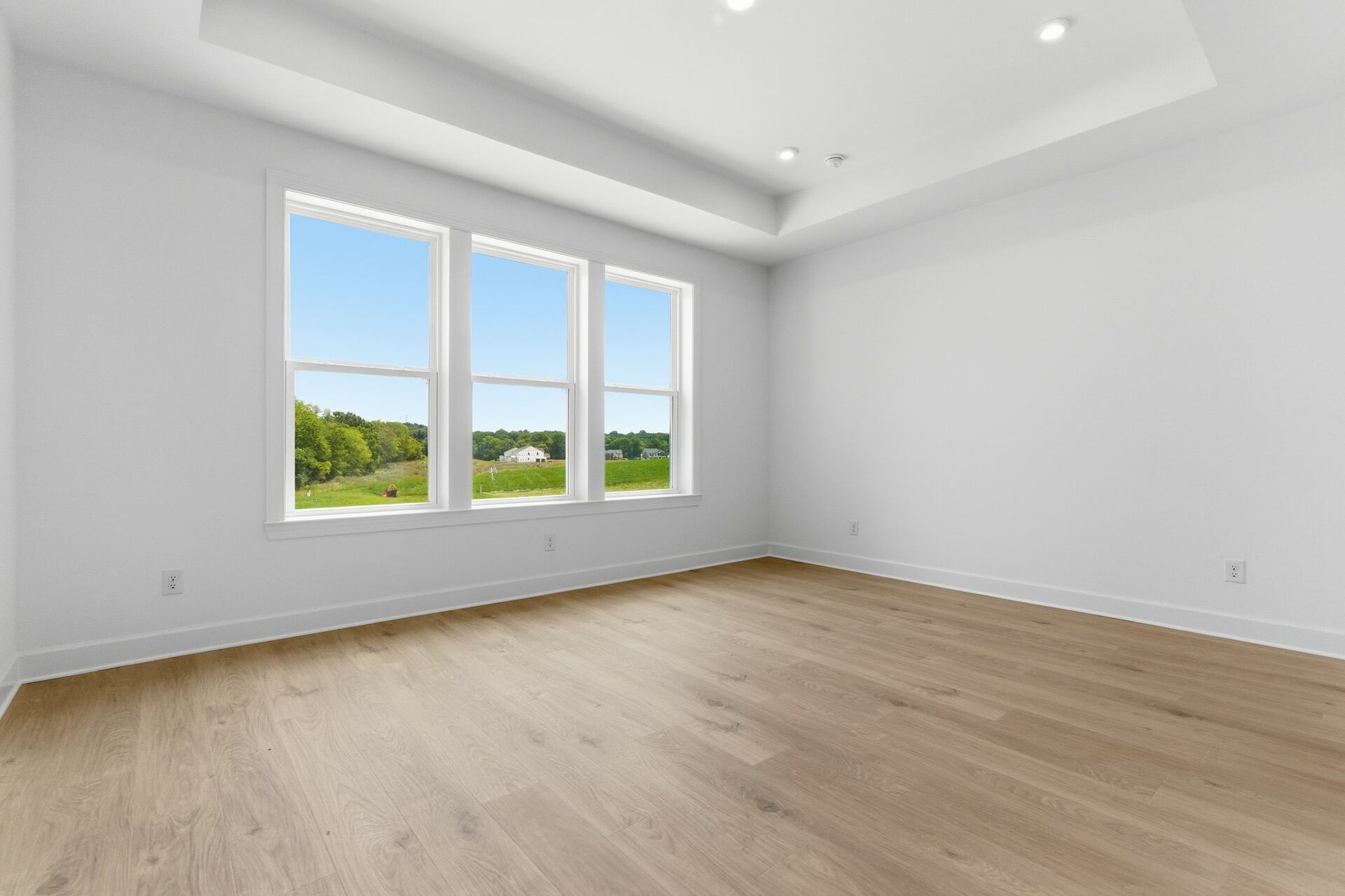 primary bedroom with hardwood floors, large windows, double door walk-in closet, and attached bathroom 