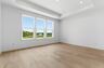 primary bedroom with hardwood floors, large windows, double door walk-in closet, and attached bathroom 