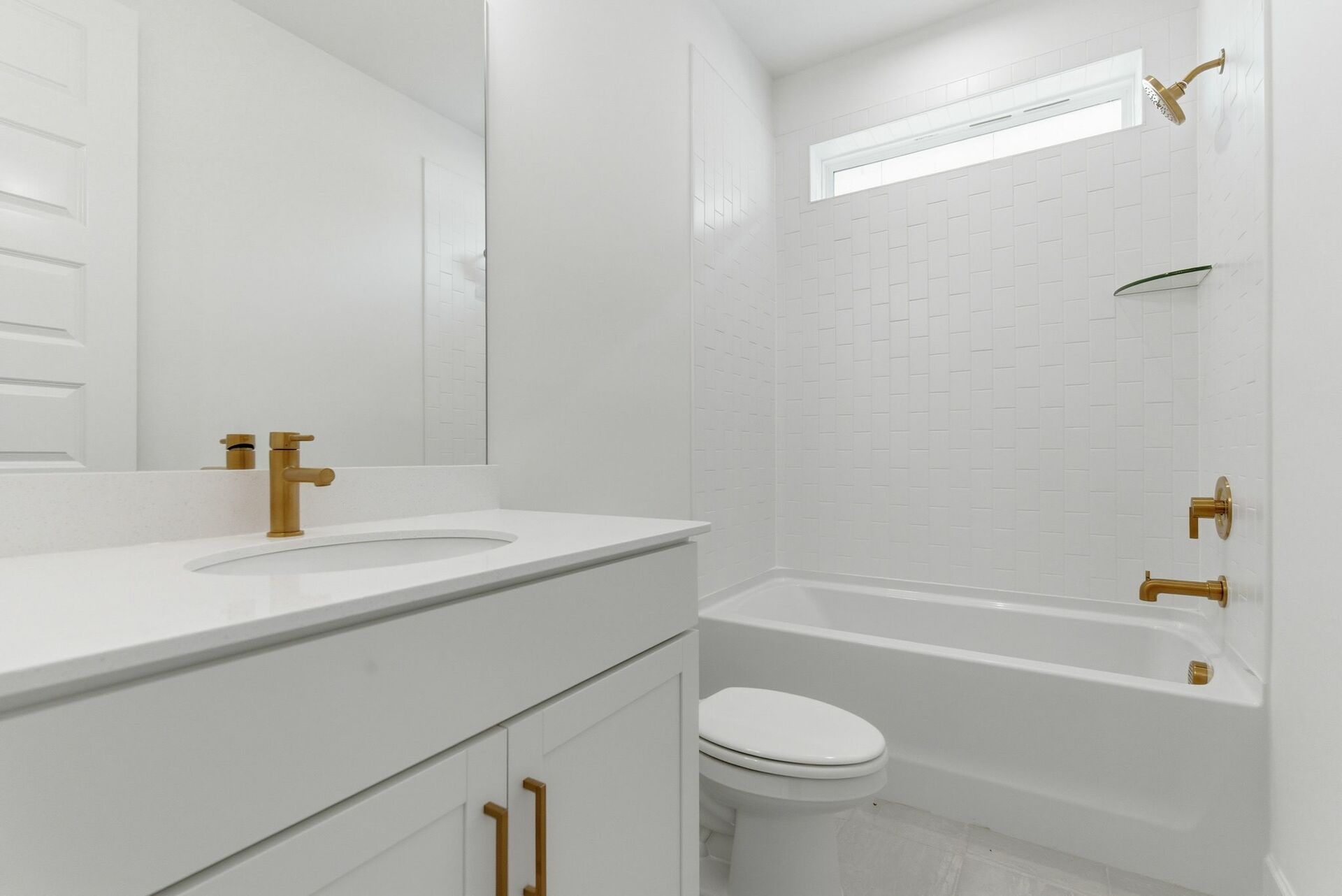 bathroom with white cabinets, large tub, and gold hardware