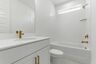 bathroom with white cabinets, large tub, and gold hardware