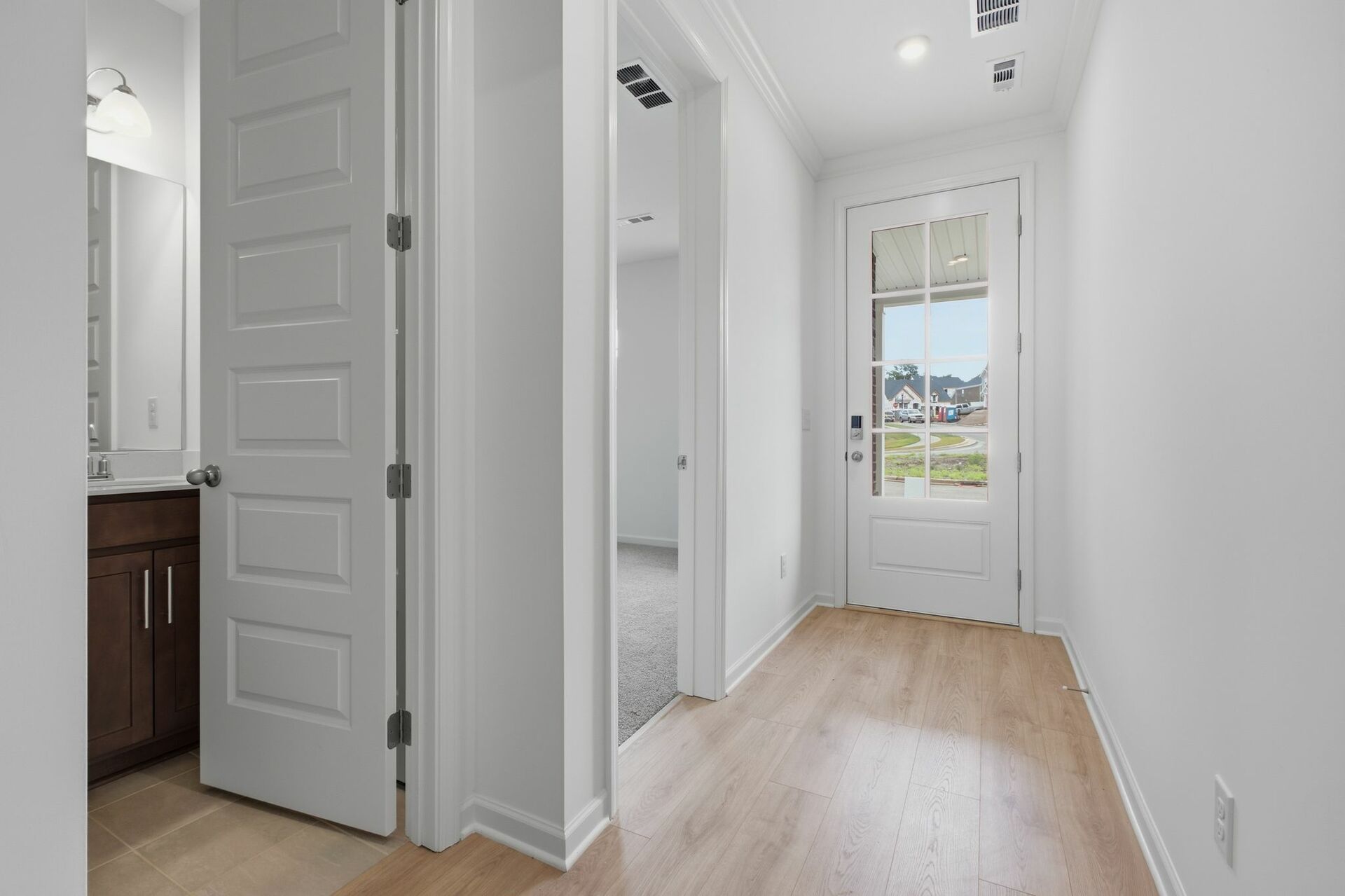 foyer with black entry door with smart lock, white walls and wood floors