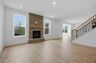 great room with stone fireplace, wood floors, and oak tread stairs with iron railing