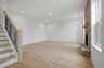 great room with stone fireplace, wood floors, and oak tread stairs with iron railing