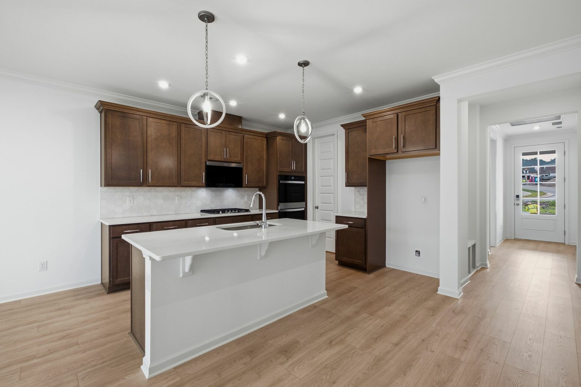 kitchen with dark brown cabinets, large island with sink, gas cooktop and microwave oven combo