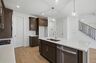 kitchen with dark brown cabinets, large island with sink, gas cooktop and microwave oven combo