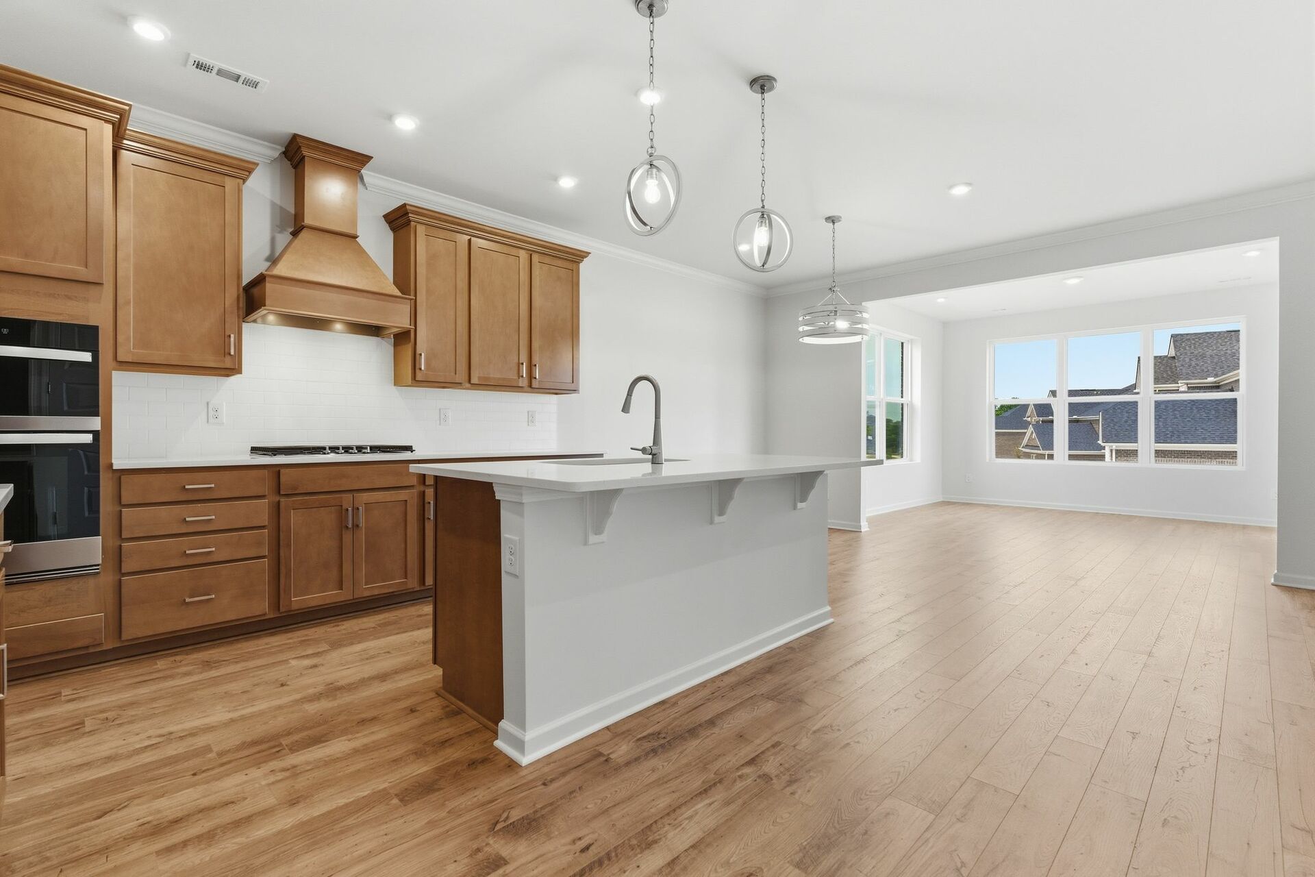 kitchen with wood cabinets, built in microwave and oven, island with sink, and stainless-steel appliances