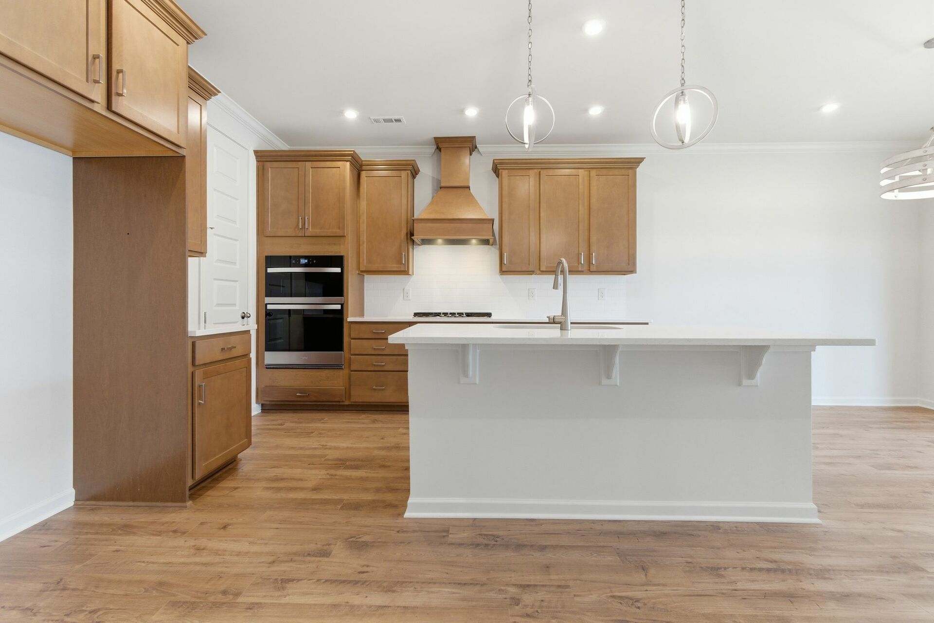 kitchen with wood cabinets, built in microwave and oven, island with sink, and stainless-steel appliances