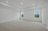 primary bedroom with carpet, large windows, tray ceiling, walk-in closet, and attached bathroom