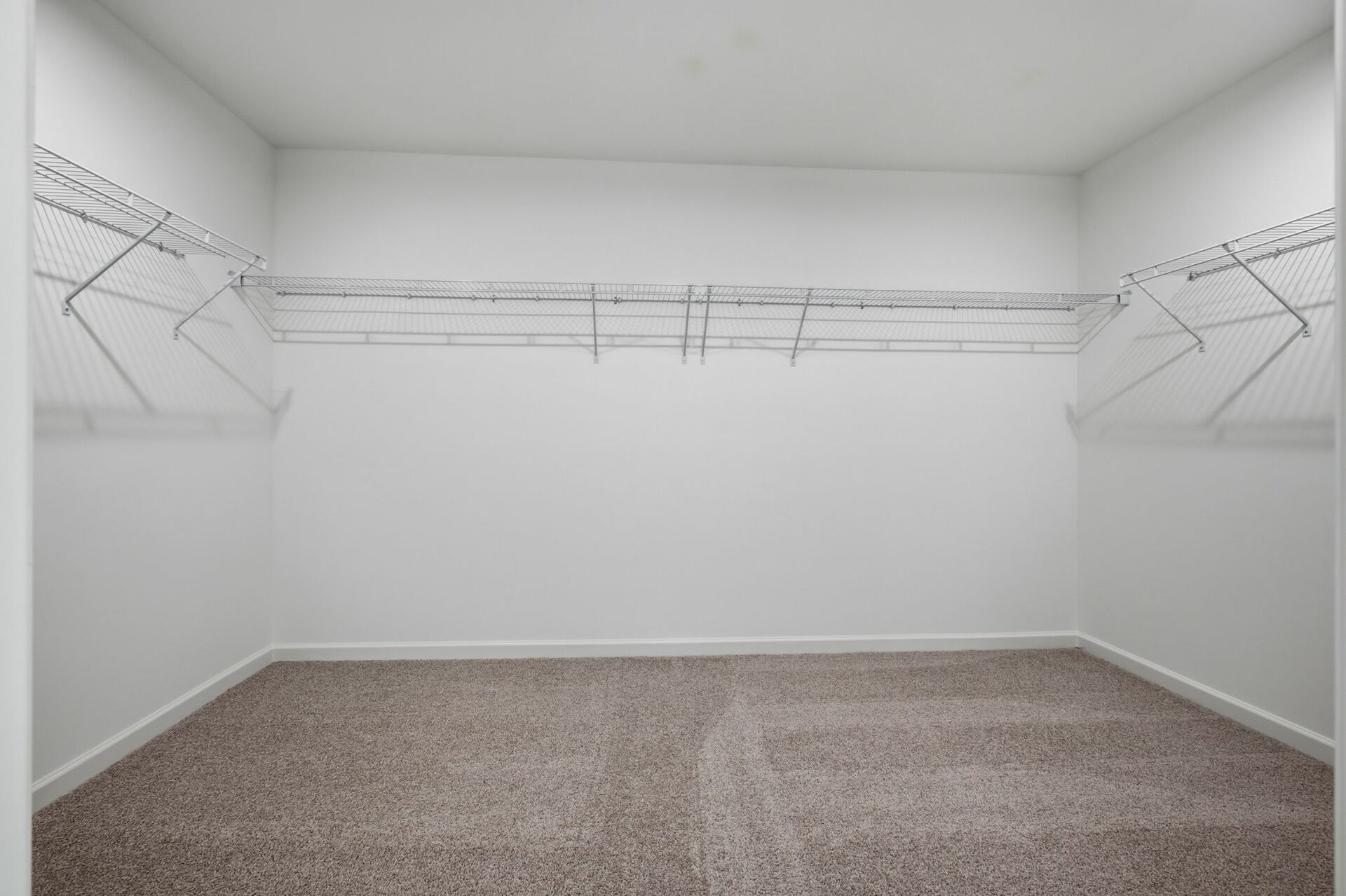 spacious walk-in closet with built in wire shelf and carpet