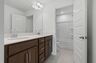 secondary bathroom with double sink vanity and tub with shelves