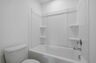 secondary bathroom with double sink vanity and tub with shelves