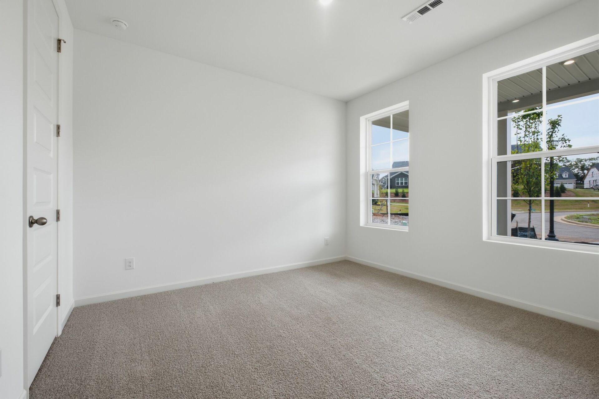 secondary bedroom with carpet, two large windows, and walk in closet