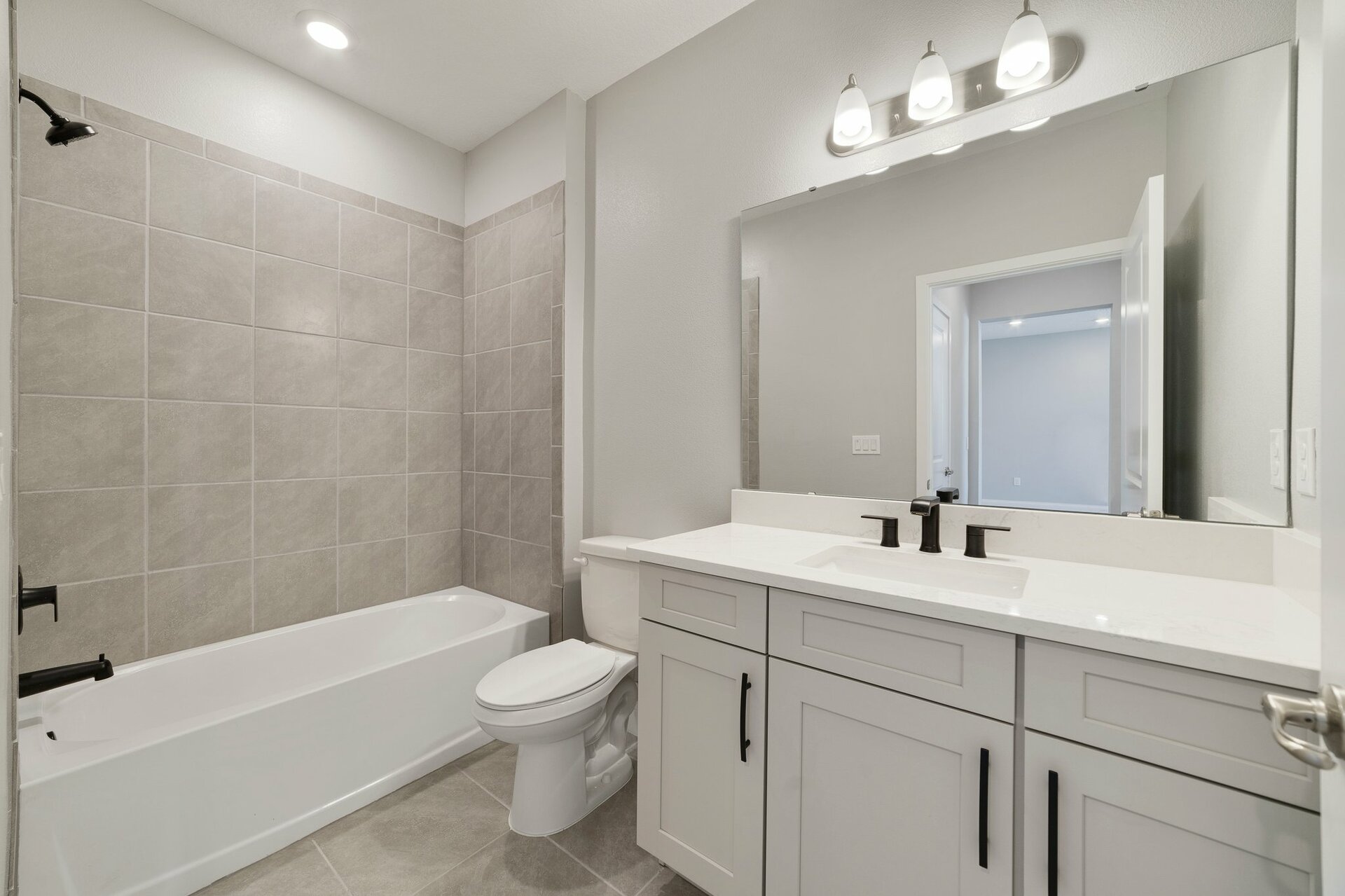 secondary bathroom with gray cabinets and a combo shower and tub