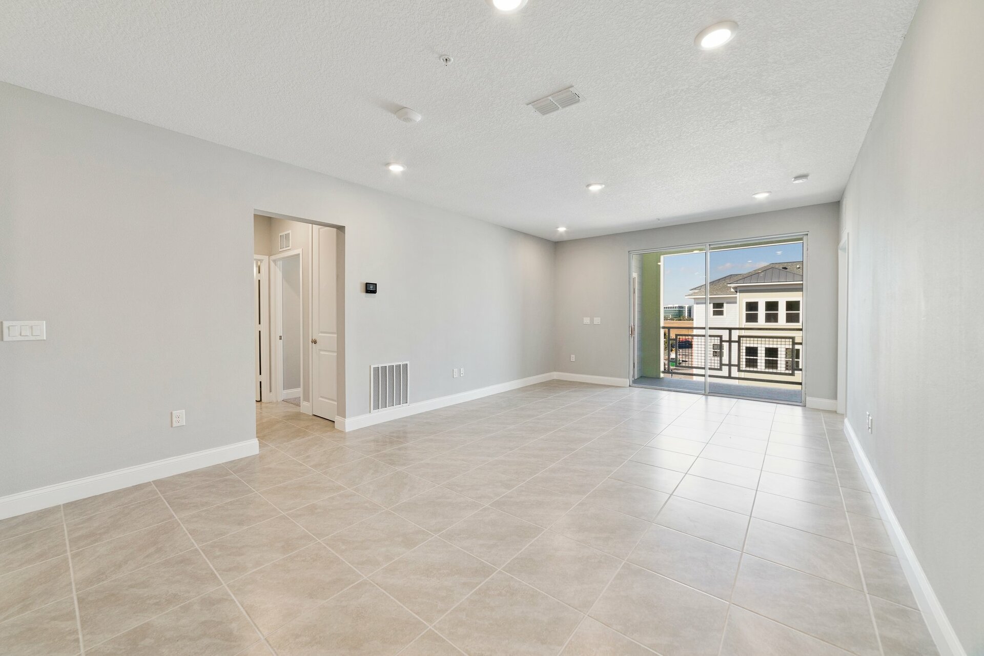 great room with tile flooring and slider leading to balcony