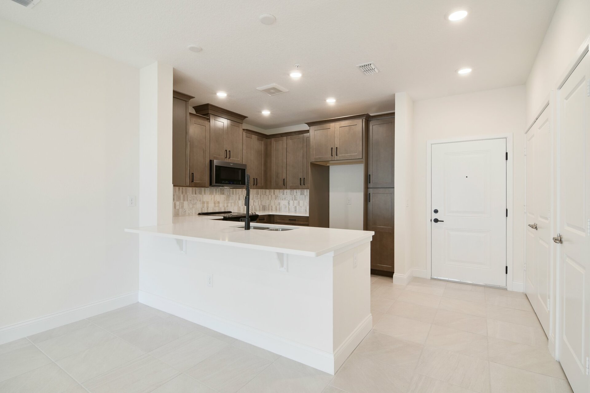 kitchen with brown cabinets, white countertops, and black hardware