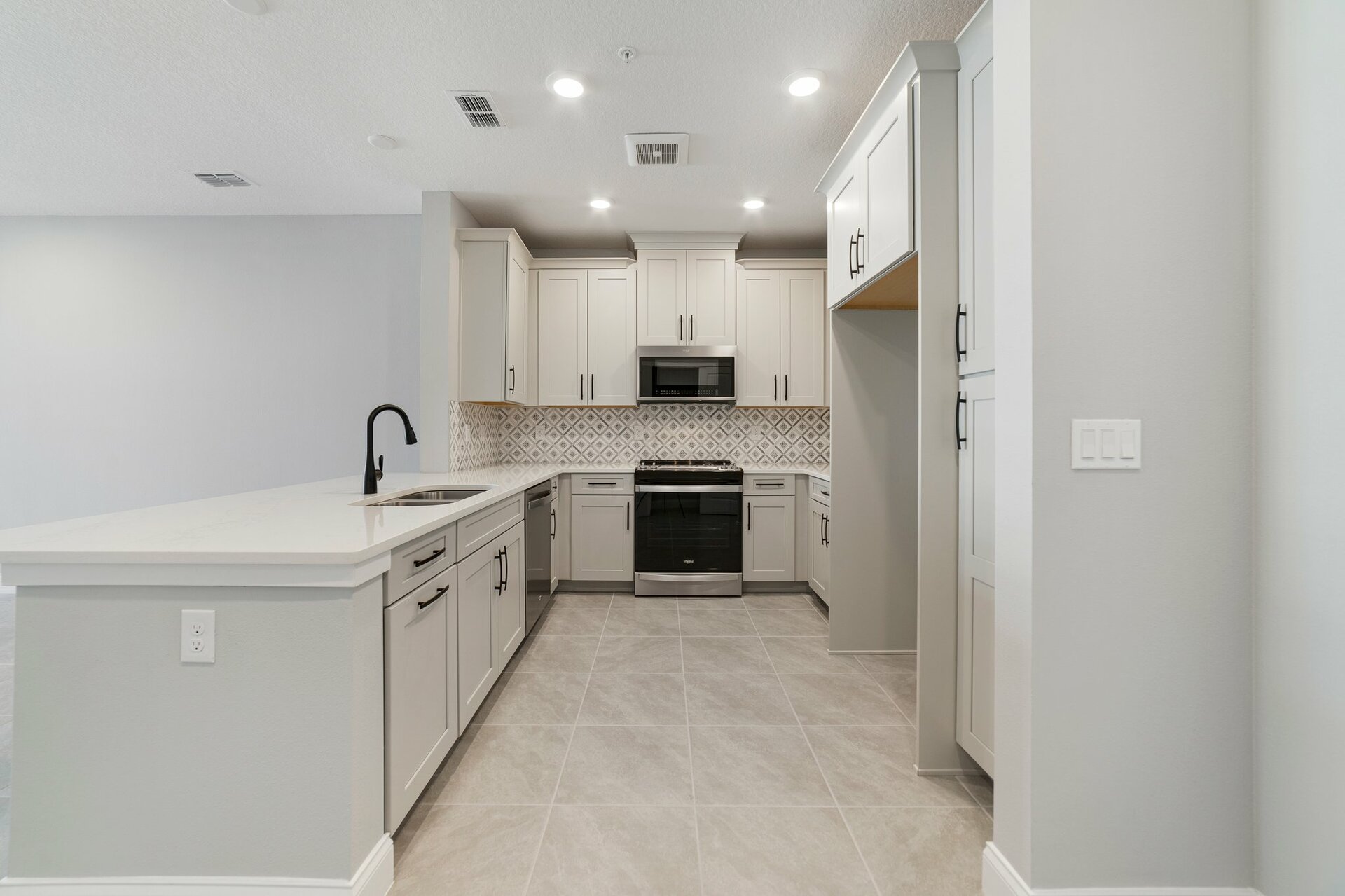kitchen with gray cabinets, crown molding, and black hardware