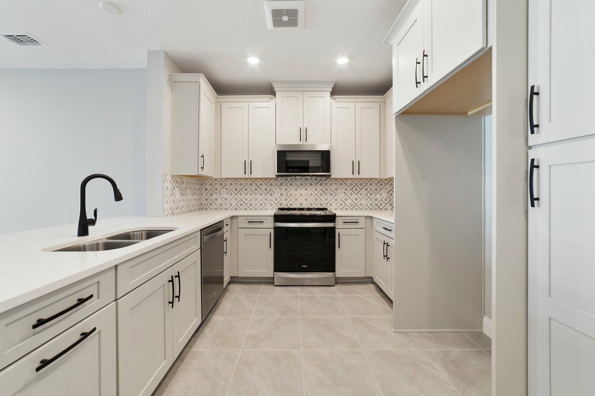 kitchen with gray cabinets, crown molding, and black hardware