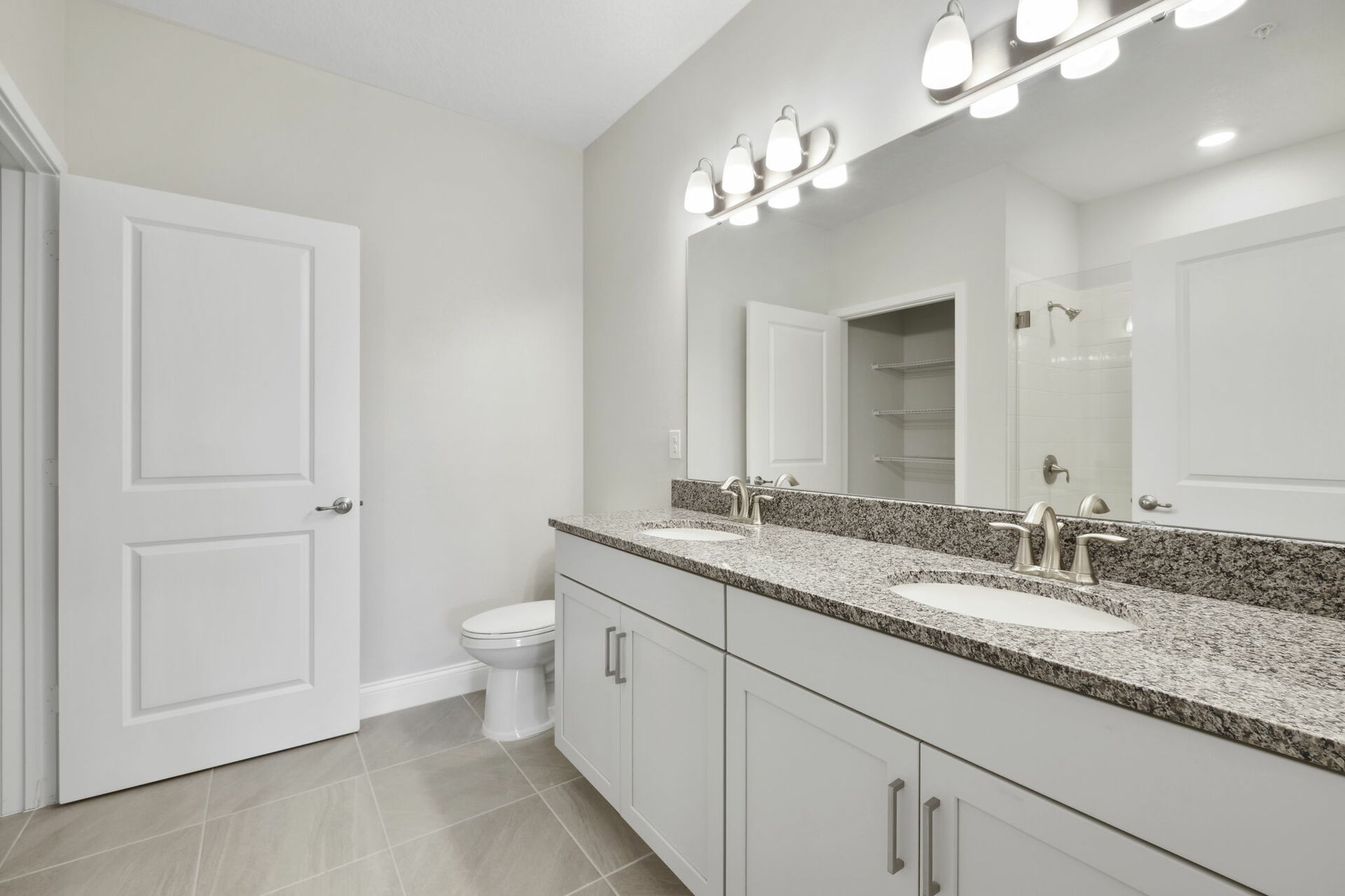 dual sink vanity with large mirror, water closet and shower