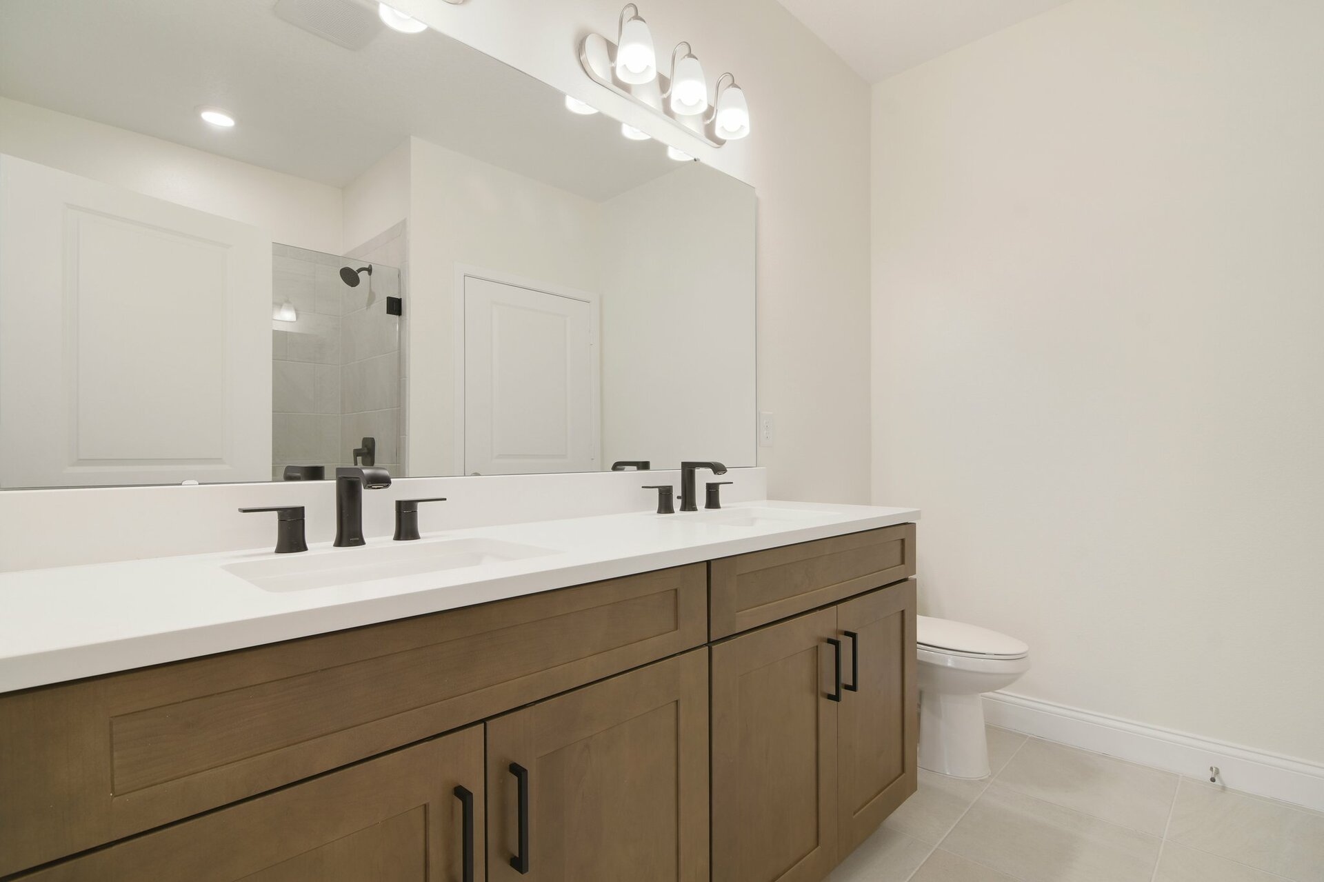 primary bathroom with tile shower and dual vanity sinks