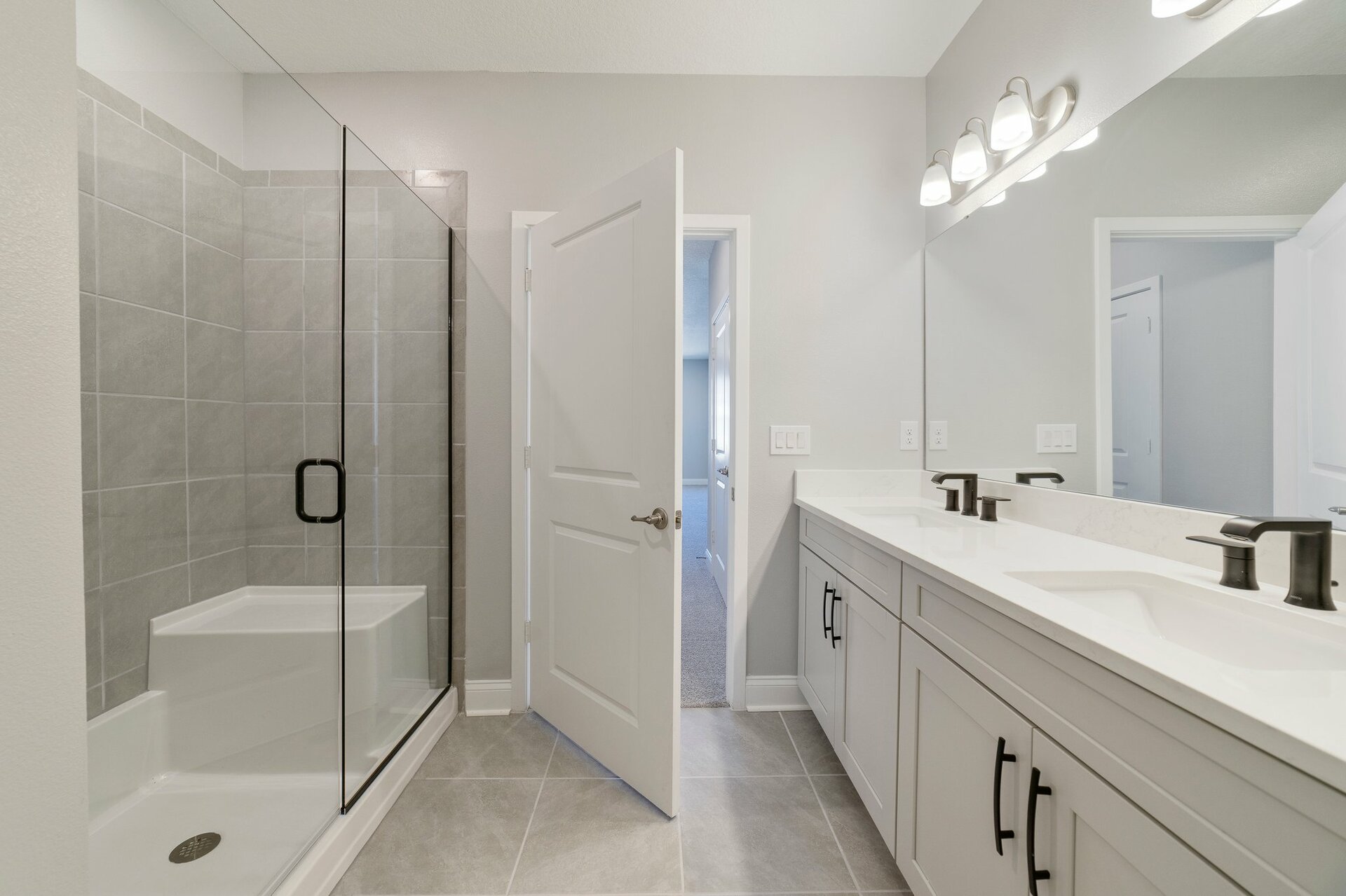 primary bathroom with gray cabinets and large walk-in shower