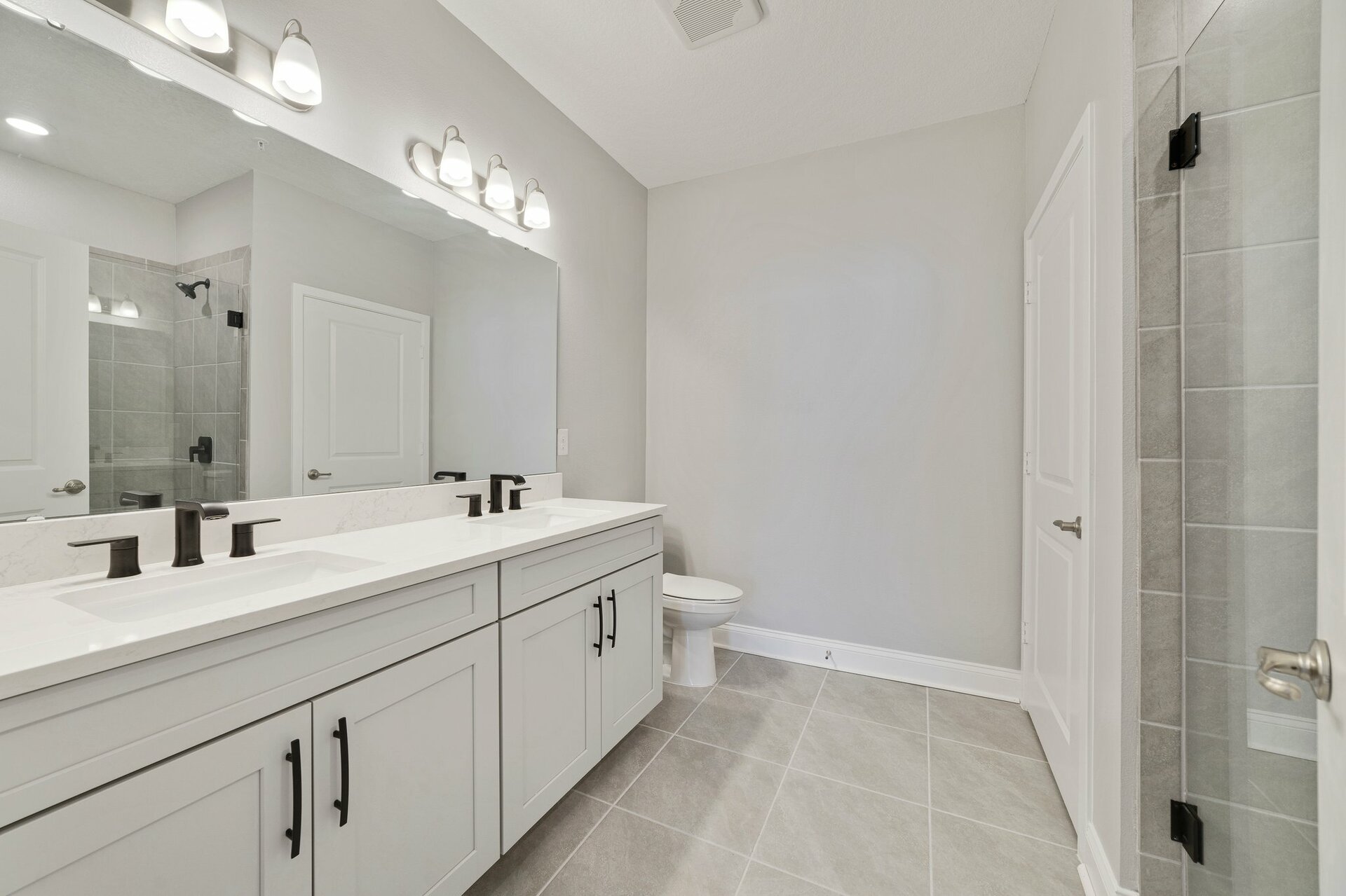 primary bathroom with gray cabinets and large walk-in shower