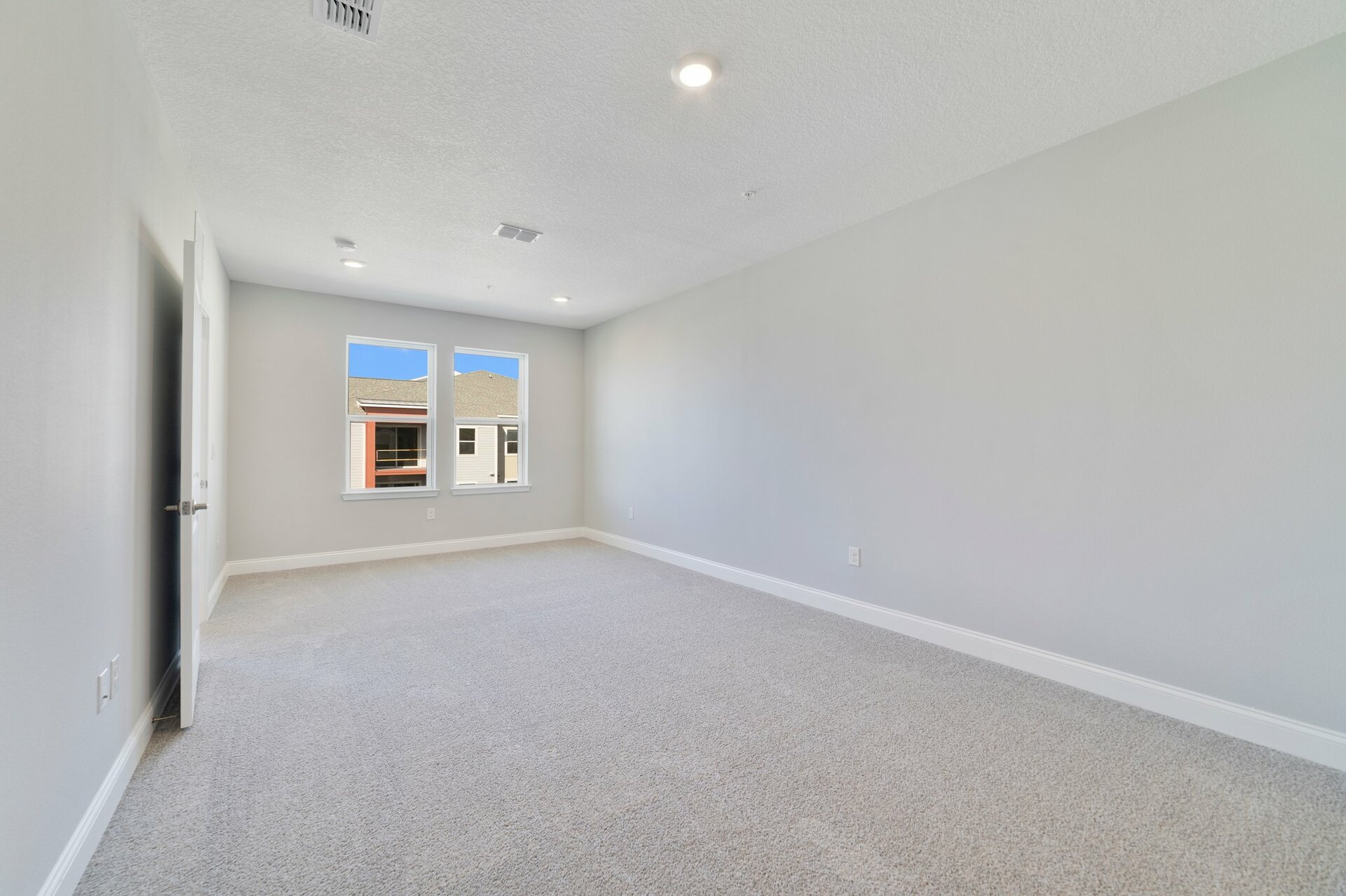 light-filled primary bedroom with carpet and two windows