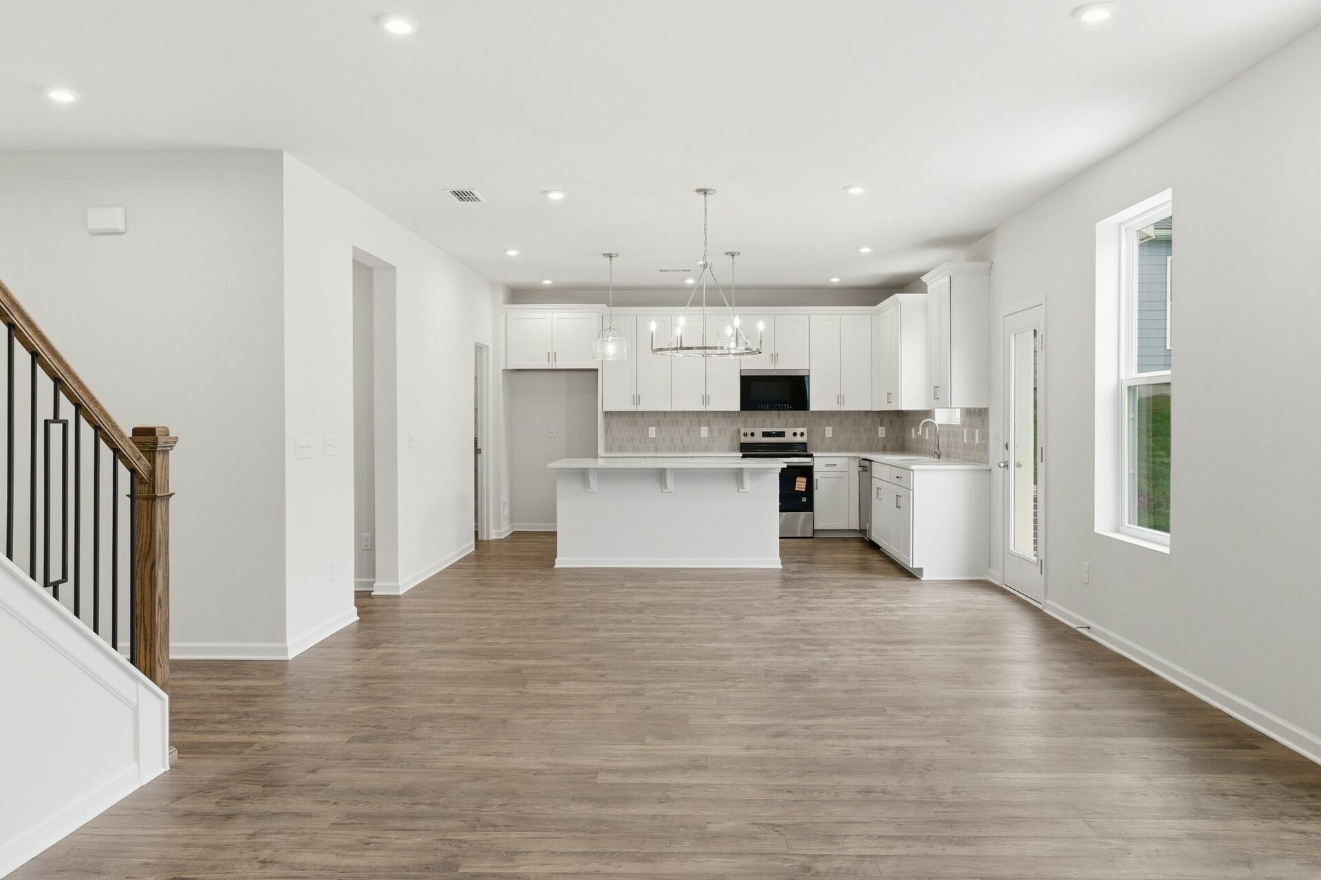 dining room with wood flooring, a view of the kitchen, and open to the great room