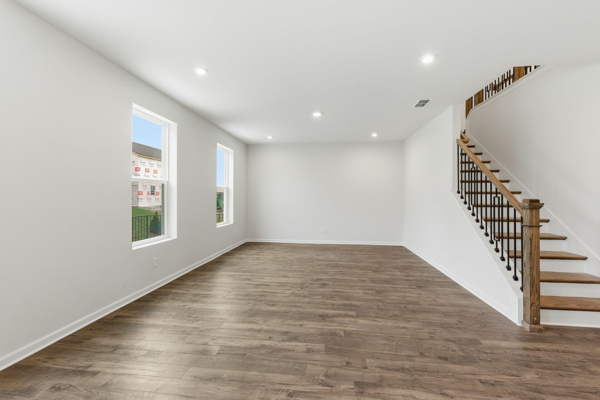 great room with wood flooring, large windows, and a view of the staircase