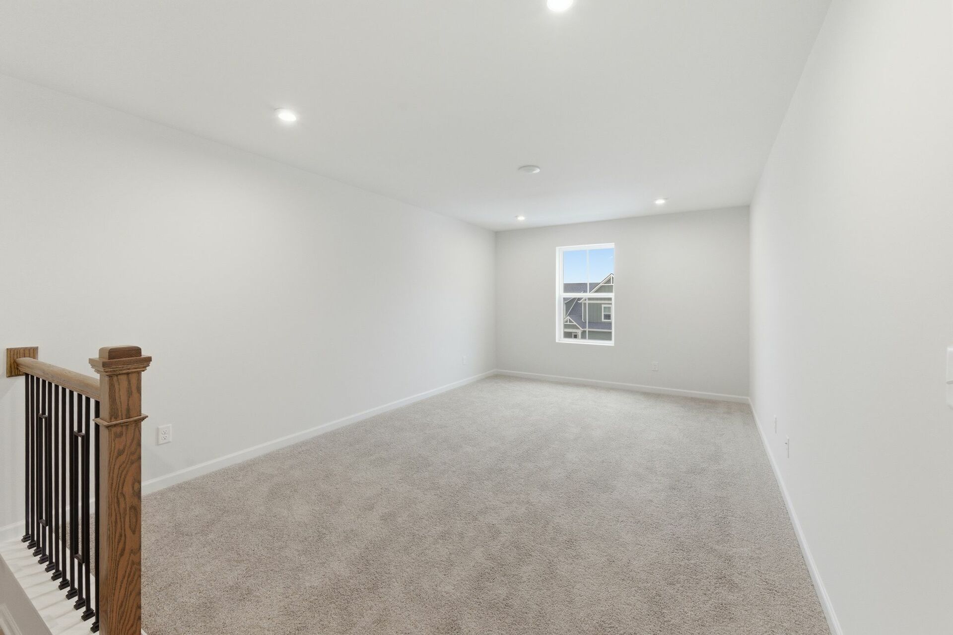 loft space with carpet flooring, white trim, and a view of the staircase