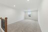 loft space with carpet flooring, white trim, and a view of the staircase