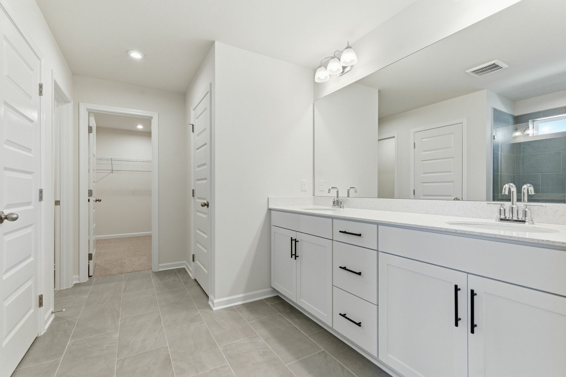 primary bathroom with dual vanity sinks and white cabinetry