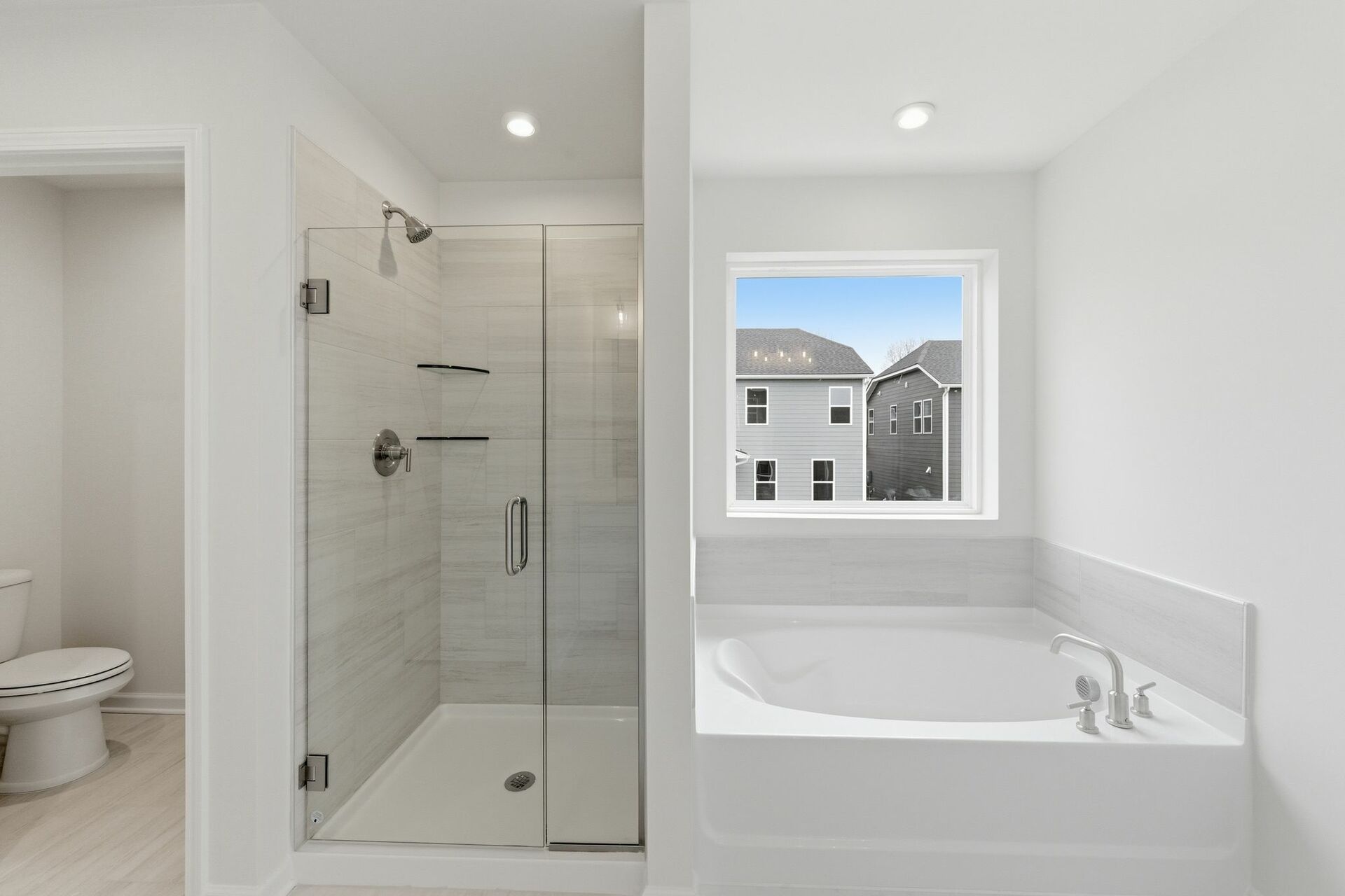 primary bathroom with tile flooring, a glass walk-in shower, and a large soaking tub