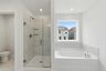 primary bathroom with tile flooring, a glass walk-in shower, and a large soaking tub