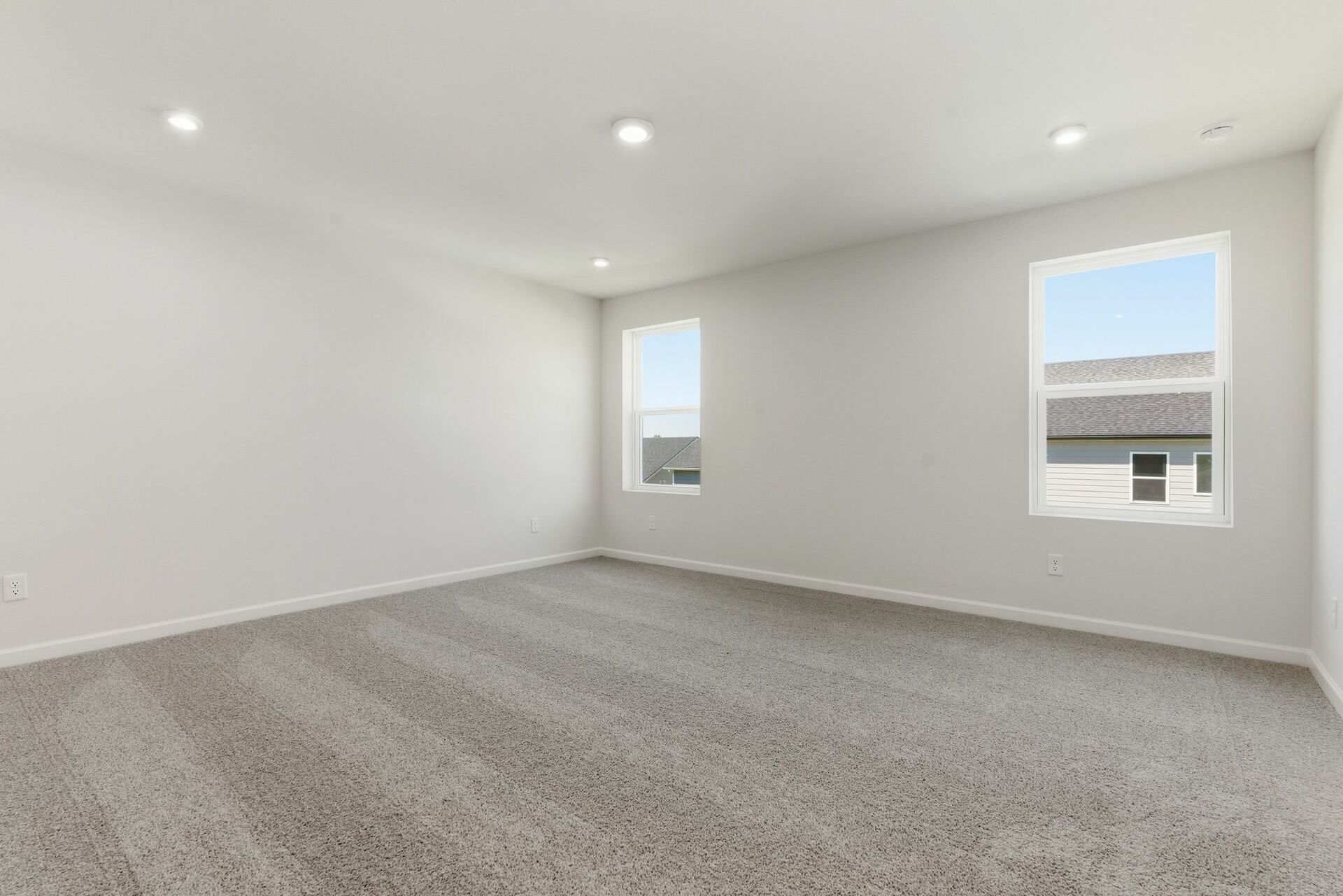primary bedroom with carpet, large windows, walk-in closet, and attached bathroom