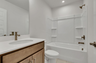 secondary bathroom with wood cabinets and white countertops