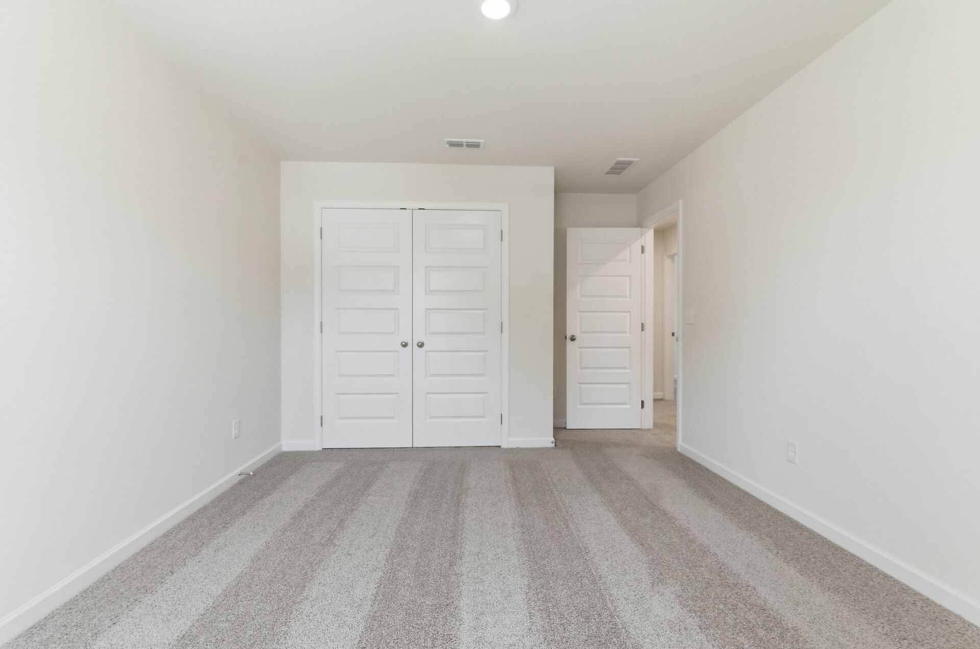 secondary bedroom with large windows, walk in closet, and carpet