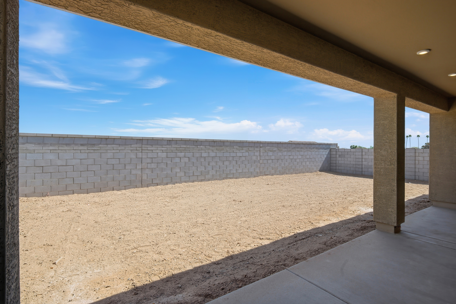spacious dirt backyard with concrete block wall