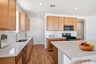 spacious kitchen with quartz countertops, brown cabinets, and stainless-steel appliances