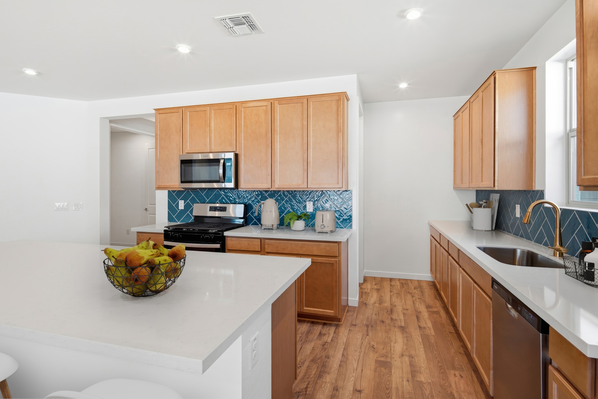 open-concept kitchen with quartz countertops, brown cabinets, and stainless-steel appliances
