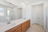 spacious bathroom with a double sink, chrome faucets, and brown cabinets