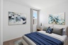 bedroom with a large bed, blue duvet cover, and blue abstract art