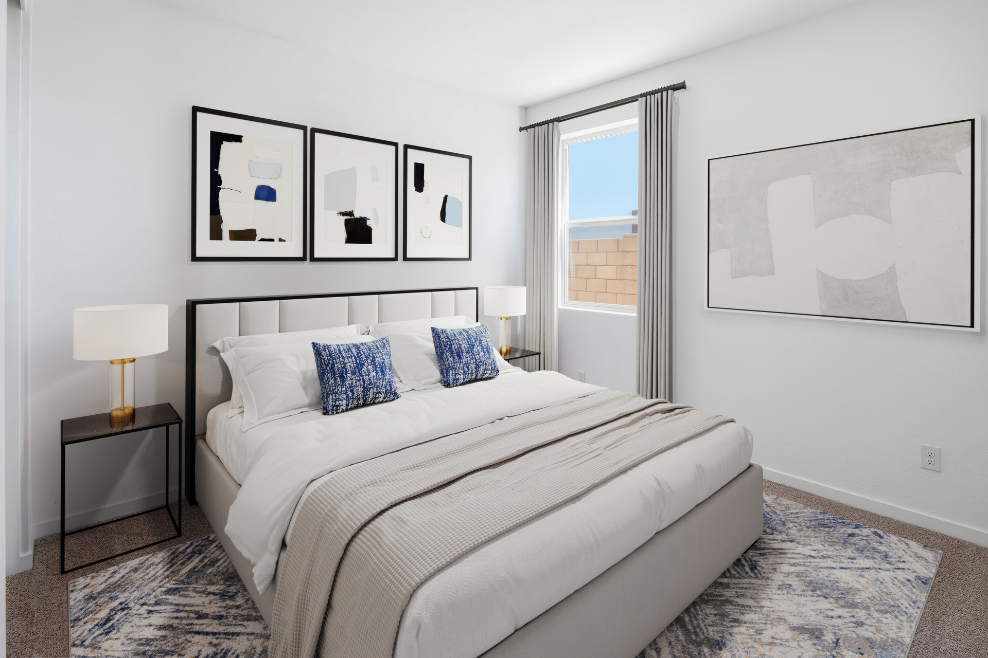bedroom with a large white bed, black nightstands, and a neutral-colored rug