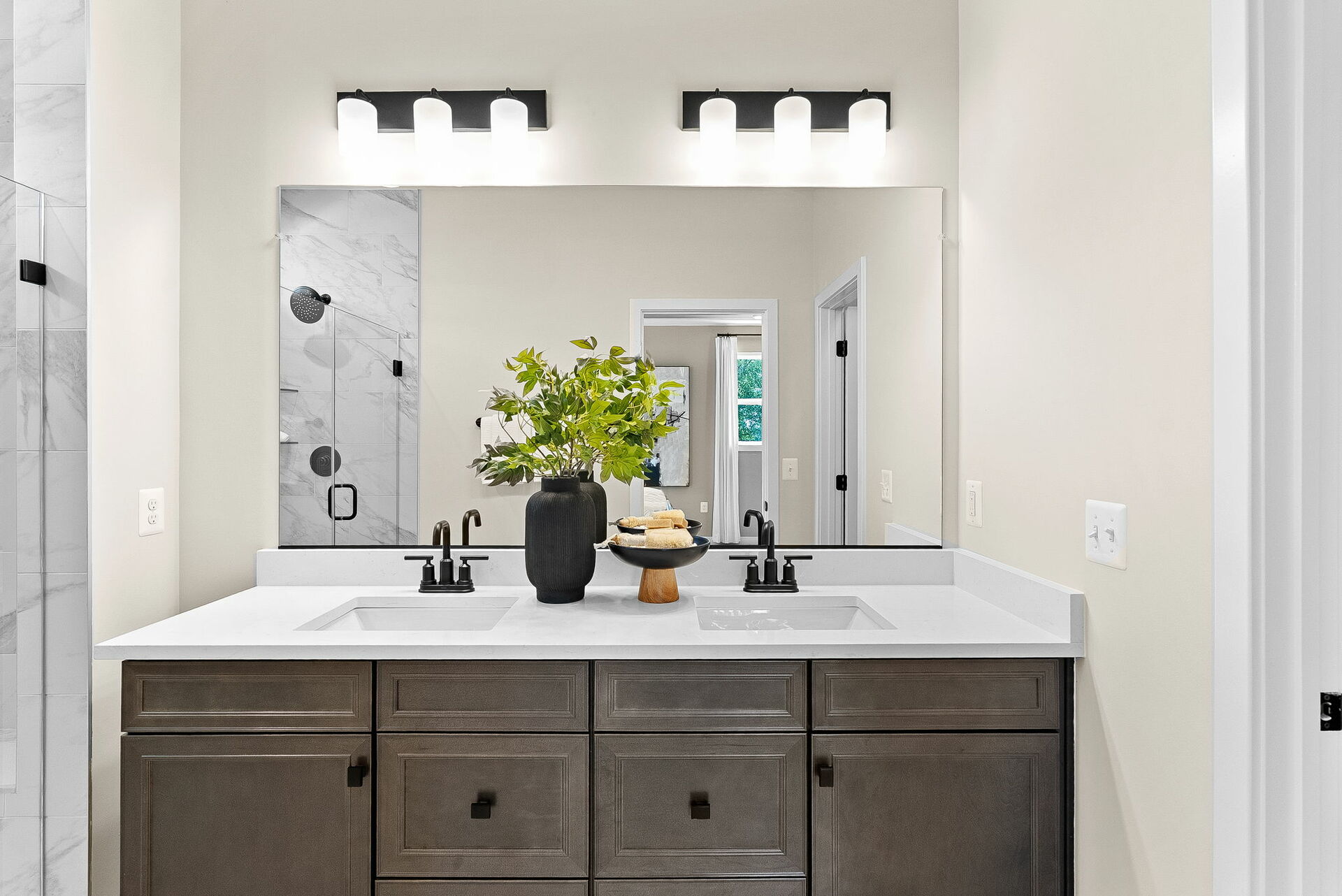 bathroom with two sinks and brown cabinets and black hardware, mirror